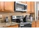 Close-up of kitchen with granite countertops, modern appliances, tile backsplash, and wooden cabinets at 11225 Godwit Ct, New Port Richey, FL 34654