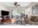 Comfortable living room with a ceiling fan, neutral paint colors, wood floor, and glass sliding door leading to outdoor patio at 11225 Godwit Ct, New Port Richey, FL 34654