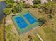 Aerial view of two blue and green tennis courts near a lake at 11225 Godwit Ct, New Port Richey, FL 34654