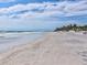 Picturesque beach scene featuring a sandy shoreline, gentle waves, and a distant pier under a partly cloudy sky at 11549 48Th Ave N, St Petersburg, FL 33708