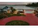 Charming home featuring a large driveway, lush lawn, and serene waterfront views at sunset at 11549 48Th Ave N, St Petersburg, FL 33708