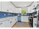 Stylish kitchen featuring white cabinetry, quartz countertops, stainless steel appliances, and a vibrant blue backsplash at 1165 63Rd S Ave, St Petersburg, FL 33705