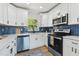 Bright kitchen features white cabinetry, stainless steel appliances, blue backsplash, and a window at 1165 63Rd S Ave, St Petersburg, FL 33705