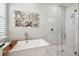 Bathroom featuring soaking tub, walk-in shower, and decorative mirror at 12409 Gentle Swan Pl, Odessa, FL 33556