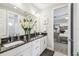 Bathroom featuring a double vanity with black countertops, white cabinets, and large mirror at 12409 Gentle Swan Pl, Odessa, FL 33556