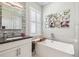 Elegant bathroom featuring soaking tub, marble accents, and stylish mirror at 12409 Gentle Swan Pl, Odessa, FL 33556