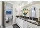Bathroom featuring a double vanity with black countertops, white cabinets, and large mirror at 12409 Gentle Swan Pl, Odessa, FL 33556
