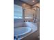 Relaxing bathroom featuring a soaking tub, glass-enclosed shower, and window with privacy blinds at 18919 Place Marquette, Lutz, FL 33558