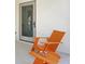 Outdoor patio with comfortable orange Adirondack chair and bowl of seashells on a sunny day at 2003 Gulf Way, St Pete Beach, FL 33706