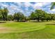 Golf course putting green with flag and mature trees and green grass at 2229 Americus W Blvd # 25, Clearwater, FL 33763