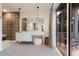 Modern bathroom featuring a glass shower, white vanity with stool, and access to a private balcony with sunset views at 311 Spring Ave, Anna Maria, FL 34216