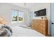 Bright bedroom features a large window, wood dresser, and mounted TV at 311 Spring Ave, Anna Maria, FL 34216