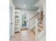 Inviting entryway features tiled floors, a wooden staircase with cable railing, and a front door view to the pool area at 311 Spring Ave, Anna Maria, FL 34216