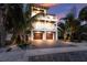 Beautiful three-story coastal home with a brick driveway, lush landscaping, and a two-car garage at 311 Spring Ave, Anna Maria, FL 34216