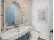 Stylish powder room featuring decorative mirror, patterned wallpaper, and modern fixtures at 311 Spring Ave, Anna Maria, FL 34216