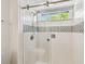 Modern shower with glass door, white tile, mosaic accents, and a window at 3398 Pinnacle S Ct, Palm Harbor, FL 34684