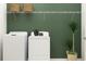 Functional laundry room with white washer and dryer, storage shelves, and stylish decor at 35105 Brackett Bnd, Zephyrhills, FL 33541