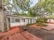 Charming backyard featuring a brick and wood patio, lush foliage, and mature trees providing ample shade at 5533 97Th N Way, St Petersburg, FL 33708