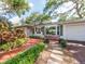 Beautiful single-story home with lush greenery, featuring a red deck and stone walkway at 5533 97Th N Way, St Petersburg, FL 33708