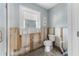 Bright bathroom featuring a toilet, window, mirror, and open wall framing for renovation at 636 Tarawitt Dr, Longboat Key, FL 34228