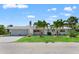 Charming single-story home with three-car garage, lush lawn, and tropical palm tree landscaping at 636 Tarawitt Dr, Longboat Key, FL 34228