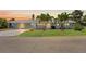 Charming single-story home with a three-car garage, lush lawn, and tropical palm tree landscaping at dusk at 636 Tarawitt Dr, Longboat Key, FL 34228