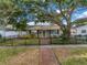 Charming home with a red brick walkway, black iron fence, and a large shade tree creating a welcoming curb appeal at 712 43Rd N Ave, St Petersburg, FL 33703
