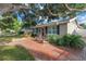 View of front exterior with brick pathway and chairs, featuring well-kept landscaping and a mature shade tree at 712 43Rd N Ave, St Petersburg, FL 33703