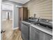 Modern laundry room features stainless steel washer/dryer, wood cabinet and wooden plank accent wall at 712 43Rd N Ave, St Petersburg, FL 33703