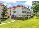 Charming condominium building with a red tile roof, manicured lawns, and white balconies at 1012 Pearce Dr # 304, Clearwater, FL 33764