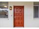 A vibrant orange front door with a unique light fixture on a stucco wall adds curb appeal to the condo at 1012 Pearce Dr # 304, Clearwater, FL 33764