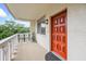 A cozy porch featuring a red door, white railings, and a view of lush greenery at 1012 Pearce Dr # 304, Clearwater, FL 33764