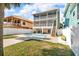 Spacious backyard featuring a refreshing pool, paver patio, and views of the multi-story home with dual screened porches at 12312 Lagoon Ln, Treasure Island, FL 33706