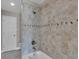 Bathroom featuring tiled walls, a soaking tub with shower, modern fixtures, and an adjacent toilet room at 12312 Lagoon Ln, Treasure Island, FL 33706