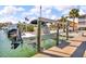 Dock featuring a boat lift with a boat, set against a backdrop of waterfront homes and clear skies at 12312 Lagoon Ln, Treasure Island, FL 33706