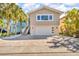 Beautiful home featuring a pristine garage, inviting staircase, and lush, tropical landscaping at 12312 Lagoon Ln, Treasure Island, FL 33706