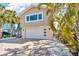 Lovely home exterior featuring an attached garage, palm trees, and a large window at 12312 Lagoon Ln, Treasure Island, FL 33706