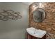 Stylish powder room featuring decorative mirror, unique lighting, and stone accent wall at 12312 Lagoon Ln, Treasure Island, FL 33706