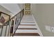 Staircase featuring wood treads and white risers, leading to the upper level with decorative artwork at 12312 Lagoon Ln, Treasure Island, FL 33706