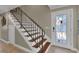 Welcoming foyer staircase featuring stained wood steps and a decorative front door with glass details and iron handrail at 12312 Lagoon Ln, Treasure Island, FL 33706
