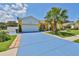 Bright yellow home featuring a blue driveway, a two-car garage, and a palm tree in the front yard at 1301 Flaxwood Ave, Brandon, FL 33511