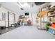 View of the organized two car garage, featuring workout area, television, storage shelves, and epoxy flooring at 13319 Dorado Shores Ave, Riverview, FL 33579