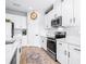 Bright kitchen featuring white cabinetry, stainless steel appliances, and a quartz countertop with wood laminate flooring at 13319 Dorado Shores Ave, Riverview, FL 33579