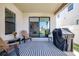 Covered patio with comfortable seating, grill, and sliding glass doors leading to living room at 13319 Dorado Shores Ave, Riverview, FL 33579