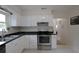 Well-maintained kitchen with white cabinets, stainless steel appliances, and a view into the hallway at 1345 Springdale St, Clearwater, FL 33755