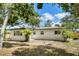 The back of the home features a large, grassy backyard with mature trees and a private fence at 1410 San Charles Dr, Dunedin, FL 34698