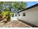 Rear exterior of home with white stucco, black trim, mature palms, and fenced yard at 1410 San Charles Dr, Dunedin, FL 34698