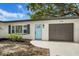 Close up of single story house with blue door, shutters and convenient attached one car garage at 1410 San Charles Dr, Dunedin, FL 34698