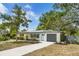 Charming single-story home with a well-manicured lawn, inviting blue front door, and convenient garage at 1410 San Charles Dr, Dunedin, FL 34698