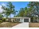 Charming single-story home with a well-manicured lawn, inviting blue front door, and convenient garage at 1410 San Charles Dr, Dunedin, FL 34698